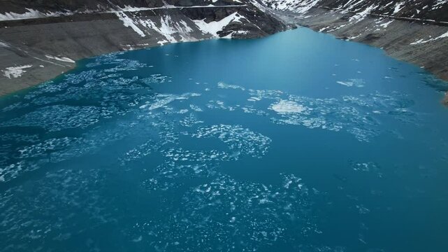 4k Drone Aerial Tilt Shot Of Frozen Ice On Top Of Vibrant Blue Glacial Water Of Lac de Moiry Dam In Grimentz Switzerland