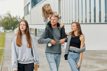 Fototapeta premium A happy family of mom, dad and two daughters are walking through the city