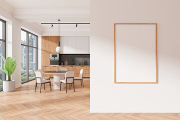Modern kitchen with wooden cabinets, round table, and chairs. Large windows with city view. Blank framed poster on white wall. Concept of art mockup. 3D Rendering.