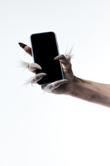 Werewolf's hand with long fingers and nails, paw holding modern smartphone with blank screen...