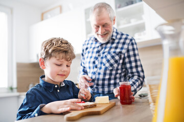 Boy and grandpa making breakfast in the kitchen. Grandfather spending time with grandson, taking...