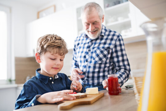 Boy and grandpa making breakfast in the kitchen. Grandfather spending time with grandson, taking care of him while parents are at work. - Powered by Adobe