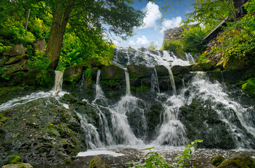 Obraz premium Small waterfall in Sweden. Moss-covered stones. Forest on the river bank. Nature
