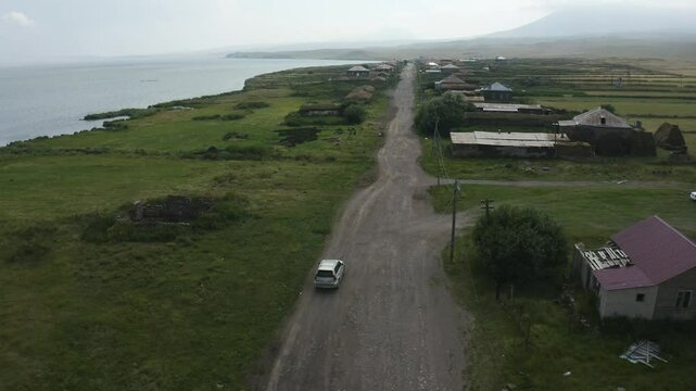 SUV Car Offroad On The Abandoned Vladimirovka Village By Paravani Lake In Georgia. Aerial Drone Shot