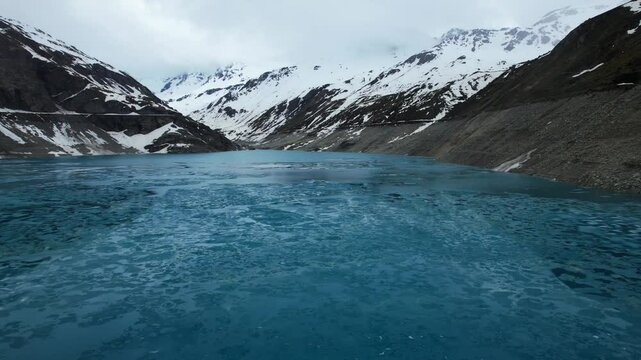4k Drone Low Shot Of Frozen Ice On Top Of Vibrant Blue Glacial Water Of Lac de Moiry Dam In Grimentz Switzerland