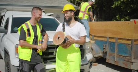 On a bustling and busy construction site, two highly skilled workers interact joyfully, showcasing their teamwork and unwavering dedication throughout the intricate house remodeling process