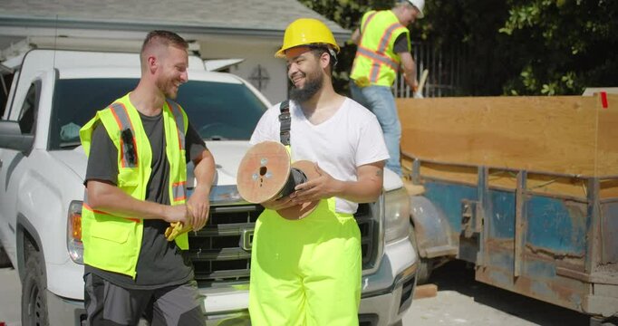 On a bustling and busy construction site, two highly skilled workers interact joyfully, showcasing their teamwork and unwavering dedication throughout the intricate house remodeling process