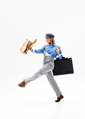 With one arm confidently holding shopping bags and carefully carrying baguette against white background, mixing fashion and function in stylish walk. Concept of shopping, Black Friday, sale season. Ad