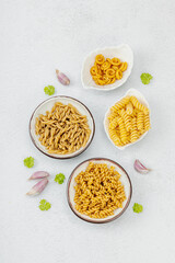 Pasta. Various kinds of uncooked pasta and noodles over light stone background. Traditional Italian