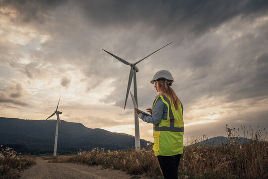 A Wind Energy Technician is meticulously inspecting a towering turbine set against a breathtaking scenic landscape, ensuring it operates efficiently and contributes to sustainable energy production