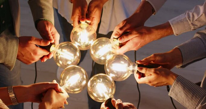 Close up hands of friends connecting light garland bulbs, team associates group, teammates joining, people searching and finding solution, team building, teamwork and support, intensive brainstorming