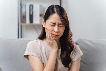 A woman with a toothache is sitting on a couch