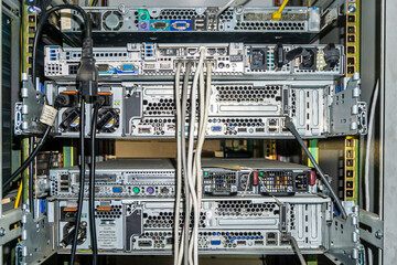 Back side of the network servers with ethernet and power cables  in the rack. Power supplies with fans and mounting rails are visible