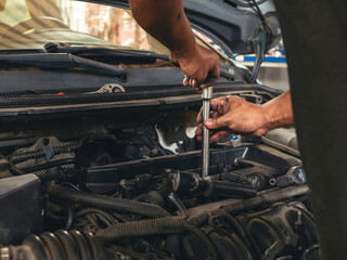 Close up Car Mechanic man hands repairing car auto repair shop. Man hands fixing machinery vehicle mechanical service. open vehicle hood checking up auto mobile. Vehicle Car maintenance engineer.