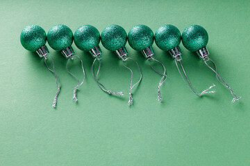 Green Glittery Christmas Balls on Green Background, Minimalist Holiday Concept, Top View, Copy Space