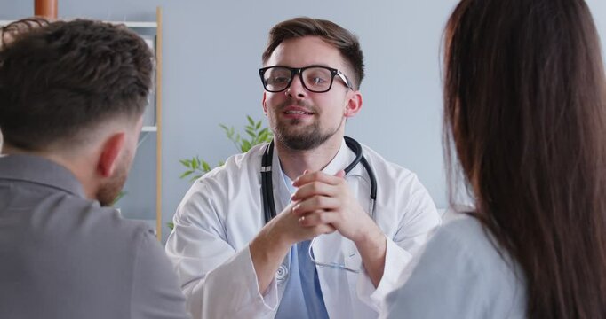 Doctor meeting, greeting, consulting young couple patient in fertility clinic, giving medical advice. Professional clinician talking to husband, wife, planning pregnancy, test, artificial insemination