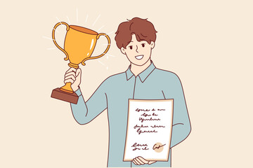 Trophies in hands of man showing certificate and gold cup received for professional or sporting achievements. Guy shows trophies proving superiority over competitors and work colleagues