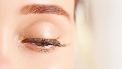 Fototapeta premium Close-up of a woman's closed eye with long eyelashes and groomed eyebrow