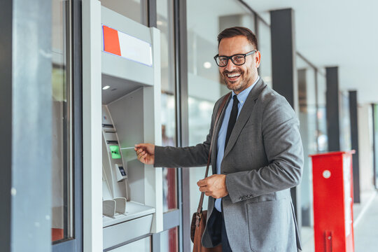 Smiling Businessman Using ATM Machine Outdoors