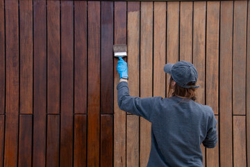 Handy woman improving house hardwood cladding with wood stain application. Do it yourself concept.