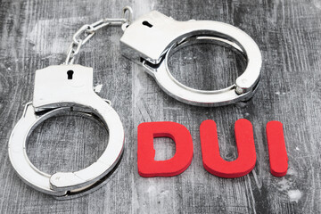 DUI message with silver handcuffs on weathered wood