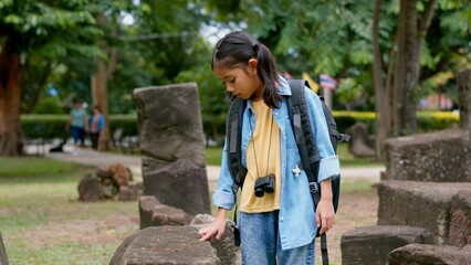 An Asian woman explores Phnom Wan Stone Temple using binoculars to admire its stunning architecture.