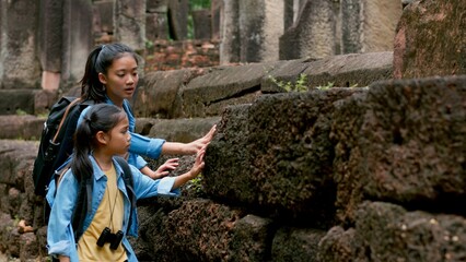 Two Asian siblings explore the Phnom Wan Stone Castle, admire the ancient architecture and take photos to record their memories.