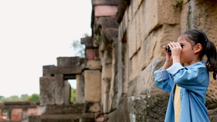 An Asian woman explores Phnom Wan Stone Temple using binoculars to admire its stunning architecture.