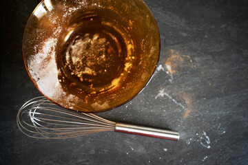 A bright and shiny whisk is positioned right next to a large bowl filled with a smooth and creamy liquid, ready for use