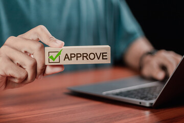 Businessman holding wooden block with text approve for document approval, assessment, approve the loan, finance agreement, loan, stamp, business.