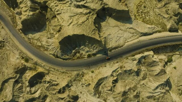 Aerial perspective showing a winding road on the Buzzi Top Makran Coastal Highway, surrounded by rugged, dramatic landscapes.