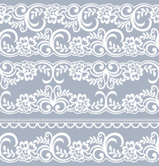 A decorative lace pattern featuring floral designs on a soft gray background, suitable for textiles or graphic design.