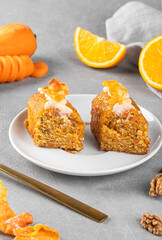 Pieces of delicious carrot cake with nuts, orange and carrot chips on a gray background. Home baking concept.