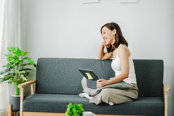 Obraz premium Smiling young woman uses social media to relax at home on the weekend. Relaxation concept