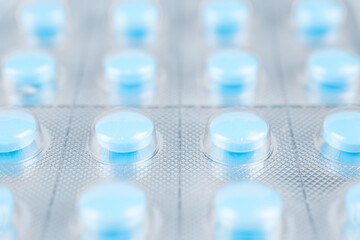 Blue tablets in blister. Macro shot. Stock photo.