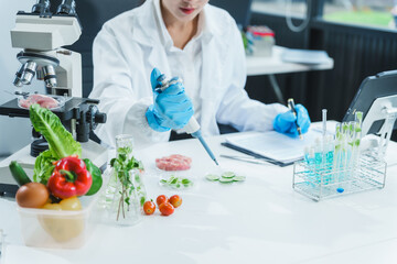 Two Asian women in a lab work on food research, using a microscope, petri dish, and test tubes...