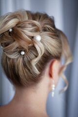 Obraz premium Back view of girl with an evening hairstyle, a high bun on blond hair,with pearls decorations