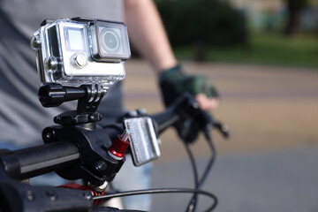 Man riding bicycle with modern action camera outdoors, closeup. Space for text