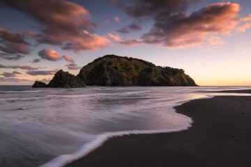 Fototapeta premium An evening sunset over sandy coastal beach in Tongaporutu, New Zealand, with Motuotamatea island in the distance