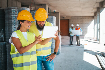 Construction Workers Reviewing Plans on Digital Tablet at Site