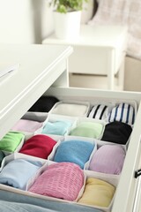 Chest of drawers with different folded clothes indoors, closeup