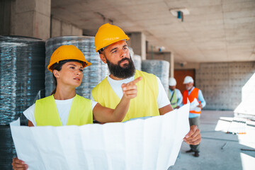 Construction Engineers Discuss Blueprints at Building Site