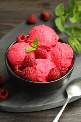 Delicious raspberry sorbet with fresh berries in bowl and spoon on wooden table, closeup