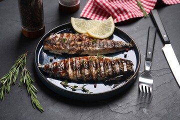 Plate with delicious grilled mackerel, rosemary and lemon served on dark textured table, closeup