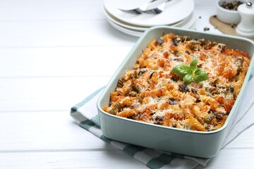Delicious al forno pasta in baking dish on white wooden table