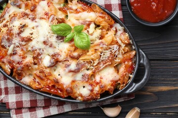 Delicious al forno pasta in baking dish on wooden table, flat lay