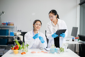 Two Asian scientists in a lab conducting food research using a microscope and lab equipment, showcasing innovation in food science