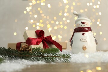 Funny snowman figure and other decor on table against blurred lights