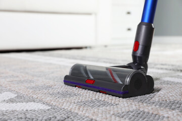 Cleaning with wireless vacuum cleaner at home, closeup. Space for text