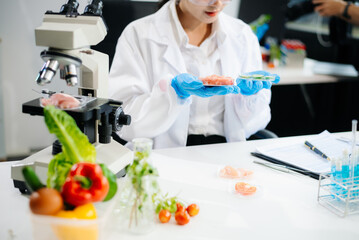 Fototapeta premium Two Asian scientists in a lab conducting food research using a microscope and lab equipment, showcasing innovation in food science